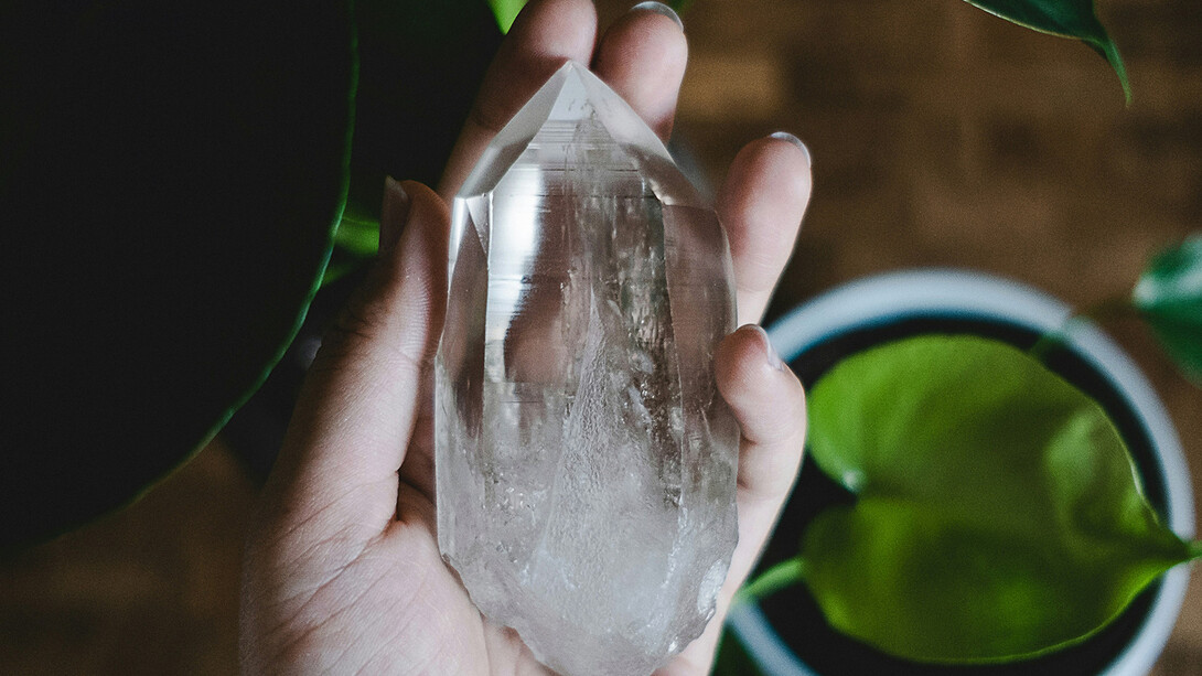 Mãos a segurar um cristal de selenita com uma luz suave à volta