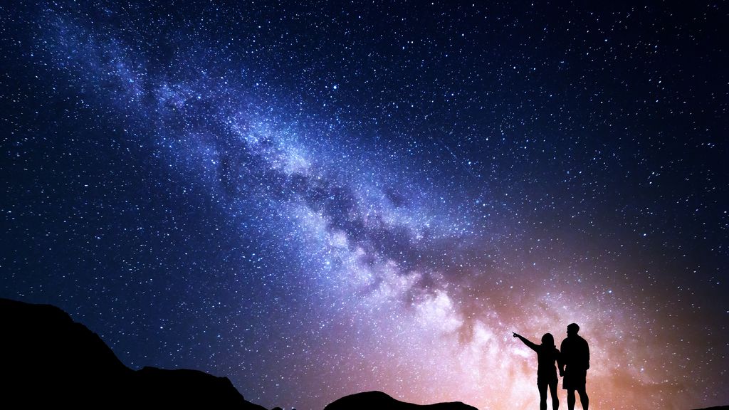 Céu estrelado com uma mão a apontar para uma constelação brilhante