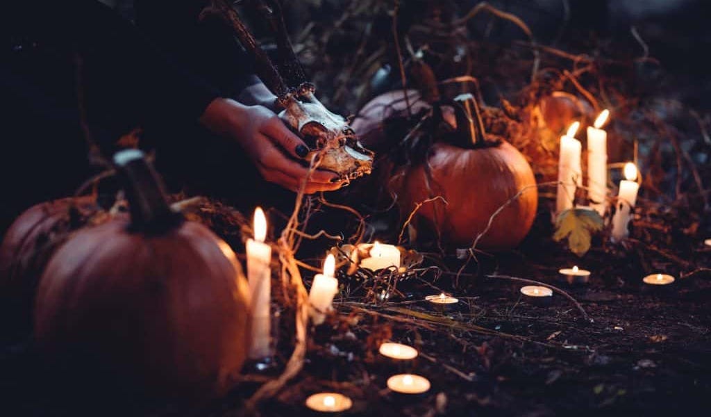 Uma abóbora de Halloween iluminada por dentro, com fumaça a sair, num ambiente escuro e místico.